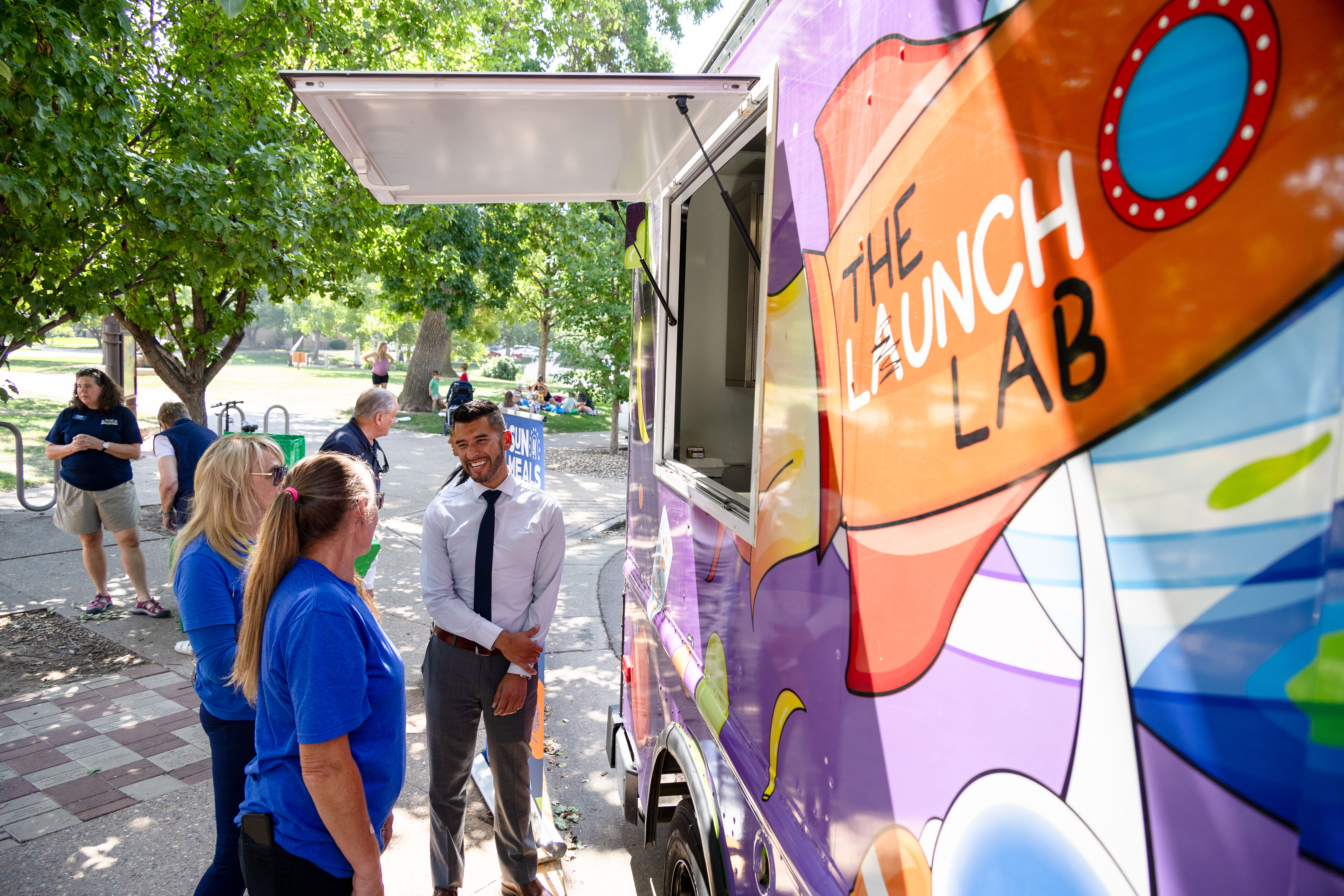 USDA's Alberto Gonzalez talks to two women outside the Food Bank for Larimer County's food truck.