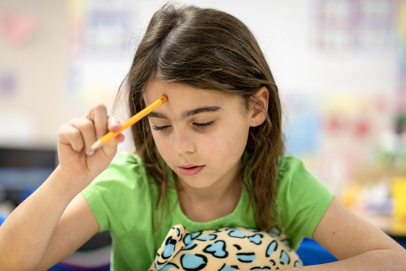 Girl with pencil works on school work. 