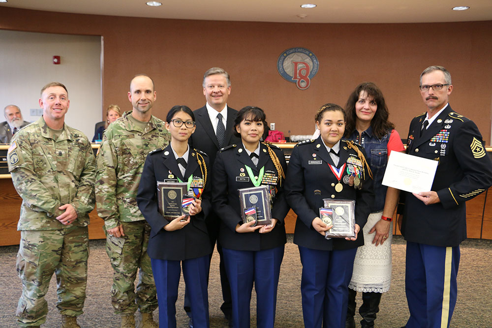 Representatives from the district, school board, and Fort Carson congratulate the JROTC team at a recent school board meeting.