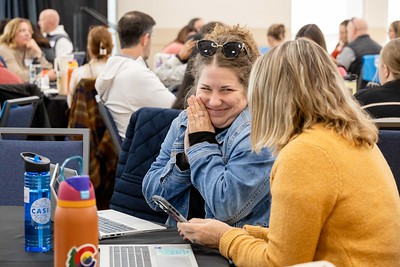 Happy educators at an event, close up of a very smiley woman talking with another woman