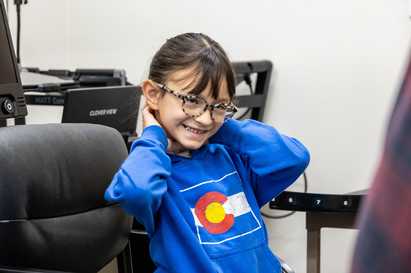 A girl wearing glasses smiles.