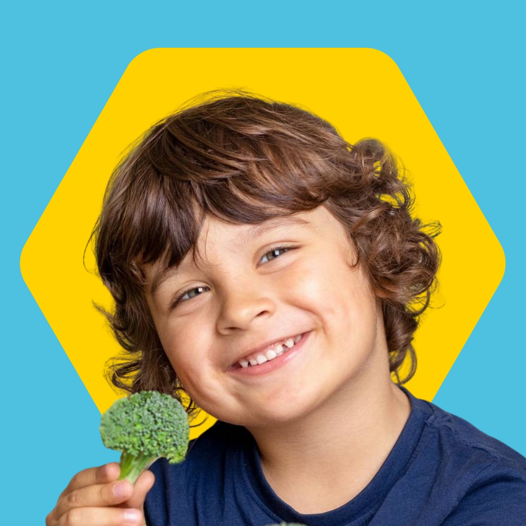 Child smiling holding broccoli